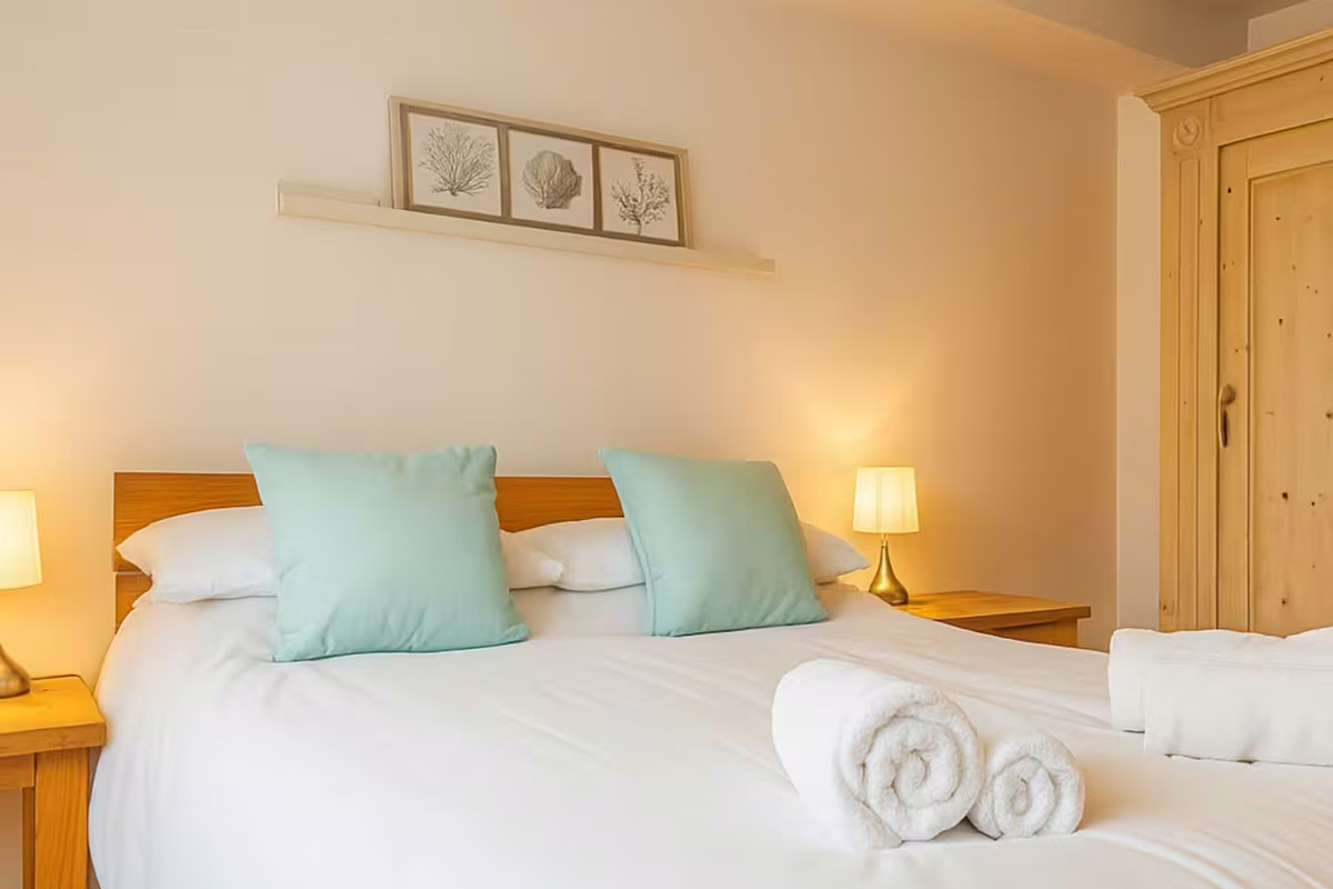 Four Degrees West – double bedroom with oak flooring and white bedding